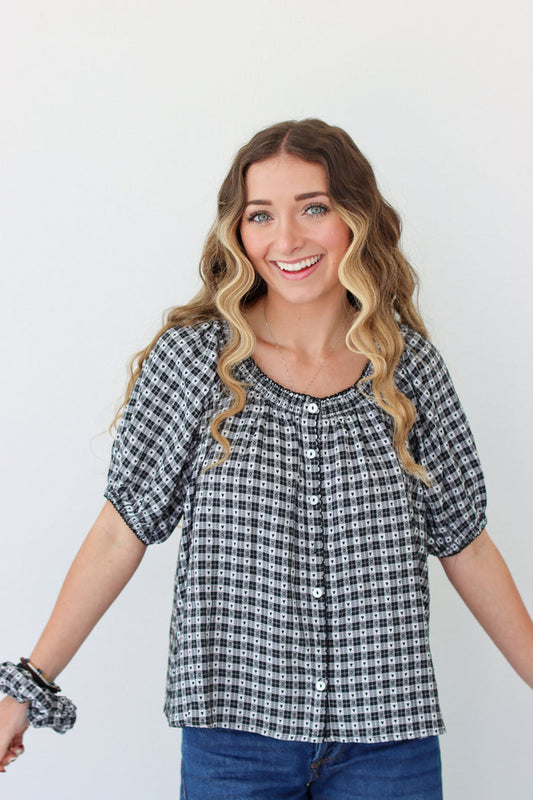Woman wearing a black and white checkered shirt with blue jeans on a plain background