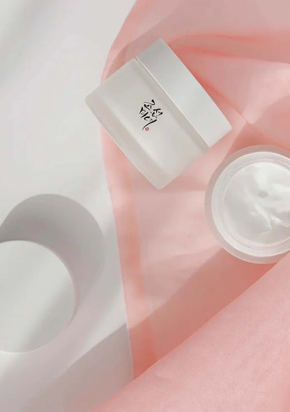Skincare product with a jar and applicator on a soft pink background