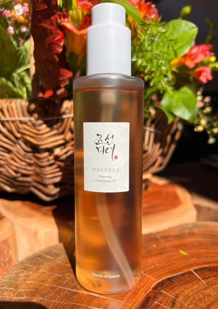 Bottle of cleansing oil with a visible label on a wooden surface with flowers in the background