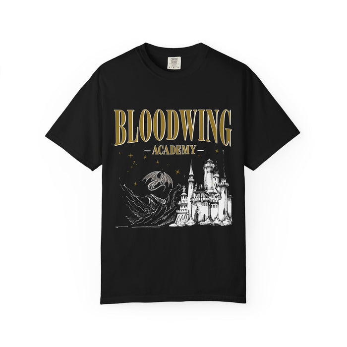 Black Comfort Colors graphic tee from thtgrlreads featuring a Bloodwing Academy design with gold gothic text, a detailed white castle, and a dragon illustration from the fantasy collection.