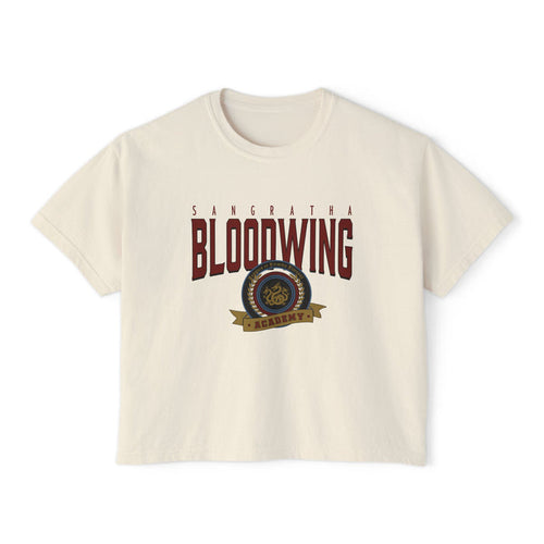 A cream-colored unisex Comfort Colors cropped t-shirt featuring a vintage wash and bold Bloodwing Academy graphic text with a circular emblem in maroon and gold, thtgrlreads.