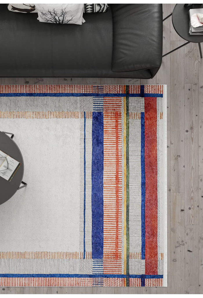 A modern living room with a black leather sofa, round gray coffee table and the Bohemian Nightscape - Washable Rug - JR1701, featuring bold geometric patterns in blue, orange, green, and red—perfect for high-traffic areas on a light wood floor.