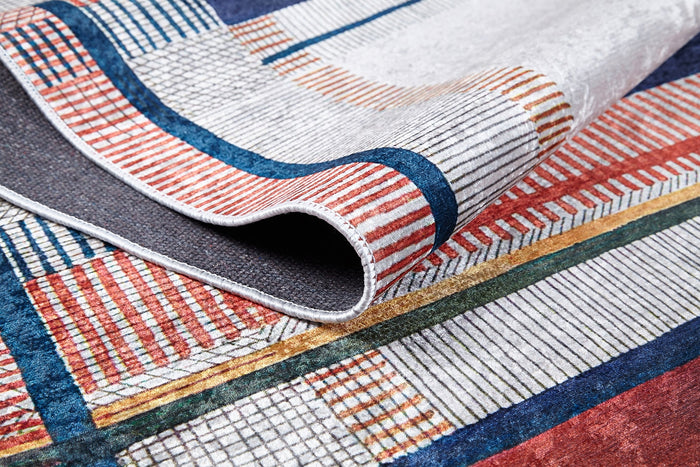 A close-up of the Bohemian Nightscape - Washable Rug (JR1701), featuring red, blue, gold, and white geometric patterns. Partially folded to highlight its texture and intricate details—ideal for high-traffic areas.