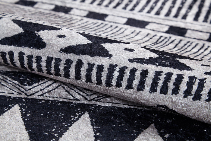 Close-up of the Bohemian Sunrise - Washable Rug - JR1713, folded to show its gray-anthracite hue with black and white geometric patterns—ideal for adding bold, durable texture to high-traffic spaces.