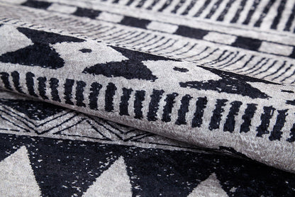 Close-up of the Bohemian Sunrise - Washable Rug - JR1713, folded to show its gray-anthracite hue with black and white geometric patterns—ideal for adding bold, durable texture to high-traffic spaces.