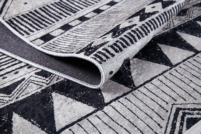 A close-up of the Bohemian Sunrise - Washable Rug - JR1713 shows its black, white, and gray geometric designs and thick texture. The gray-anthracite rug is washable, durable, and ideal for high-traffic areas.