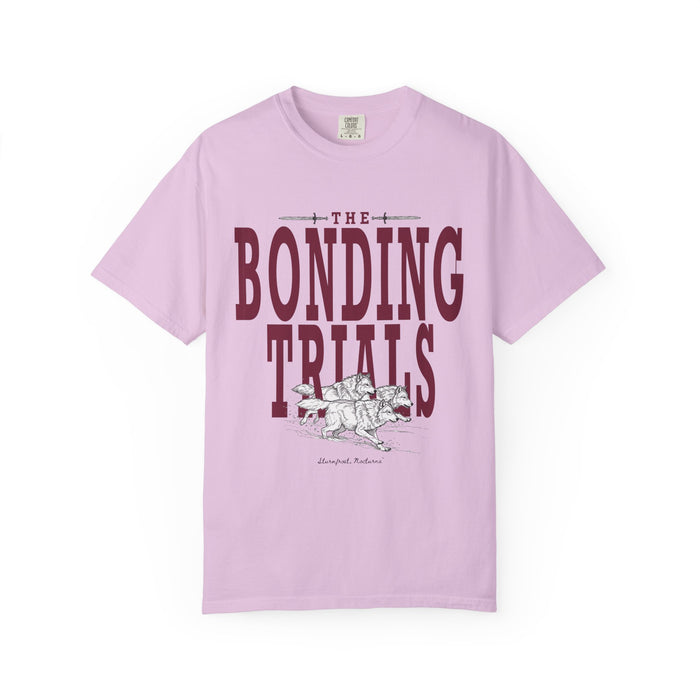 Comfort Colors graphic tee from thtgrlreads featuring vintage wash fabric in lavender with bold "The Bonding Trials" text and a detailed black and white wolf illustration, part of the Wolves of Ruin collection.