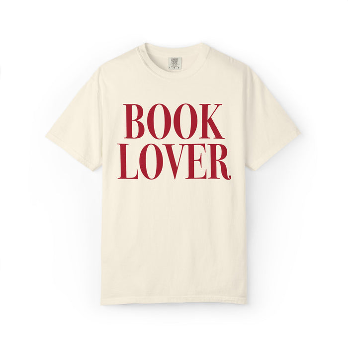 Thtgrlreads comfort colors graphic tee from the Tees collection featuring a vintage-wash cream base with bold red serif text reading "BOOK LOVER" on the front.