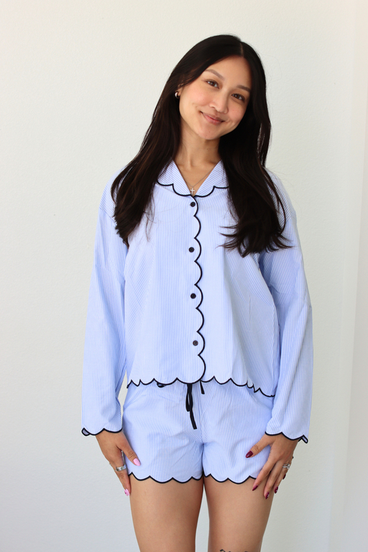 Woman wearing a light blue pajama set with black trim against a white background