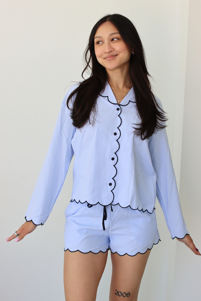 Woman wearing a light blue pajama set with black trim against a white background