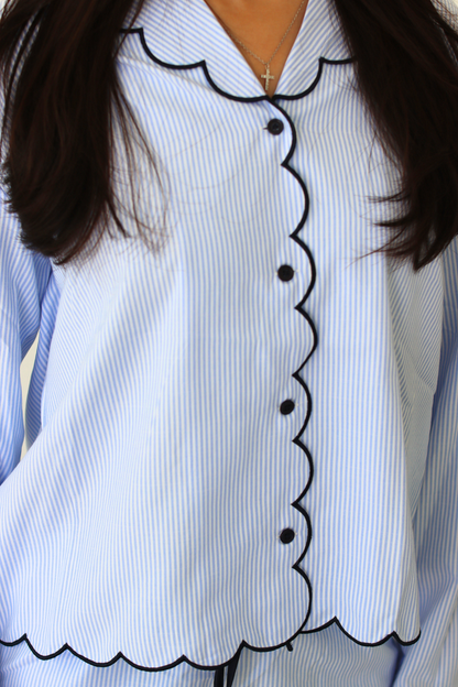 Woman wearing a light blue pajama set with black trim against a white background