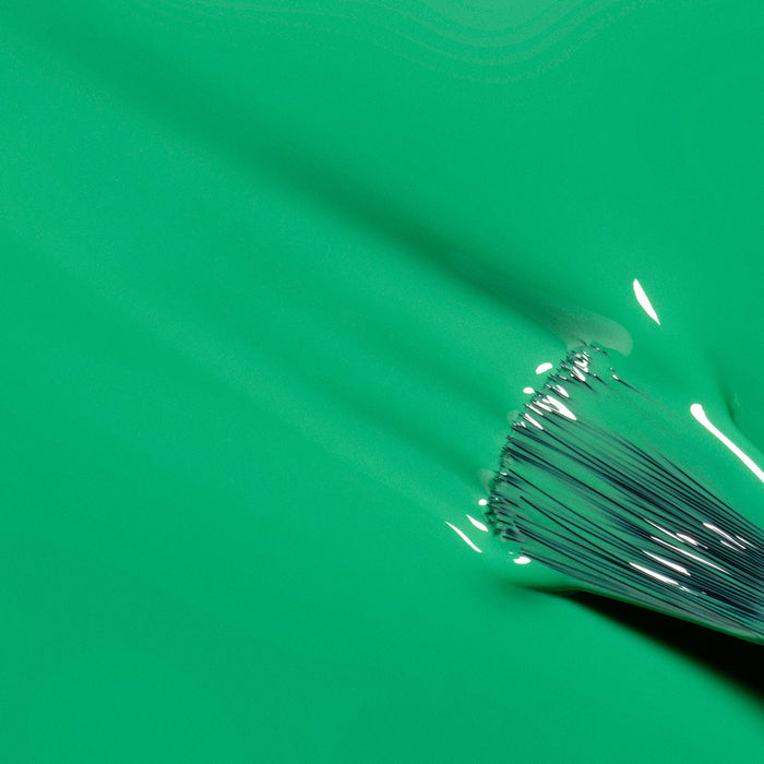 A close-up of a paintbrush smoothly applying Manucurist's Brazil electric green nail polish, showing glossy, wet texture and distinct brush bristles.