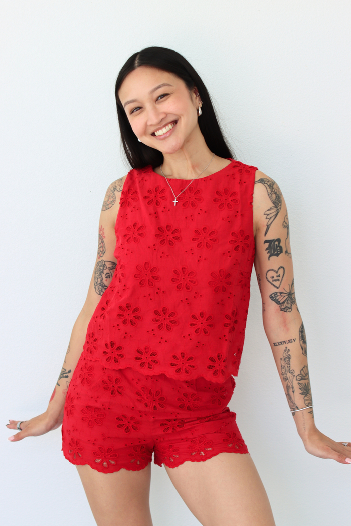 Woman wearing a red flower eyelet short set with a white background