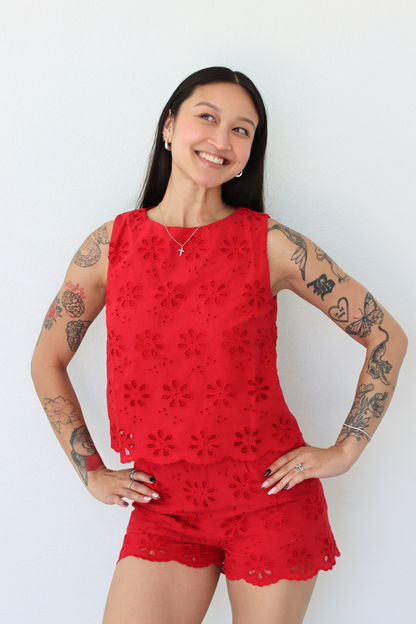 Woman wearing a red flower eyelet short set with a white background
