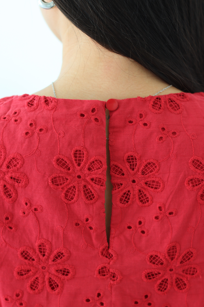 Red embroidered garment with floral patterns on a plain background