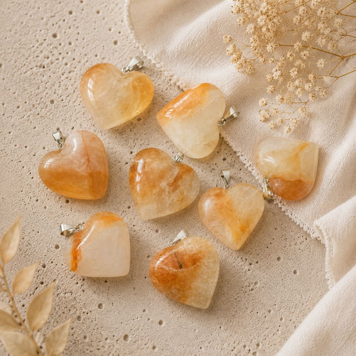 Heart-shaped stone pendants on a textured beige surface with dried flowers.
