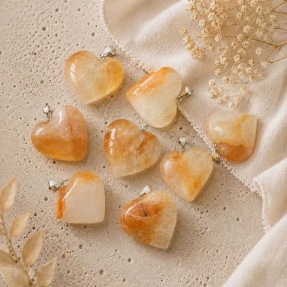 Heart-shaped stone pendants on a textured beige surface with dried flowers.