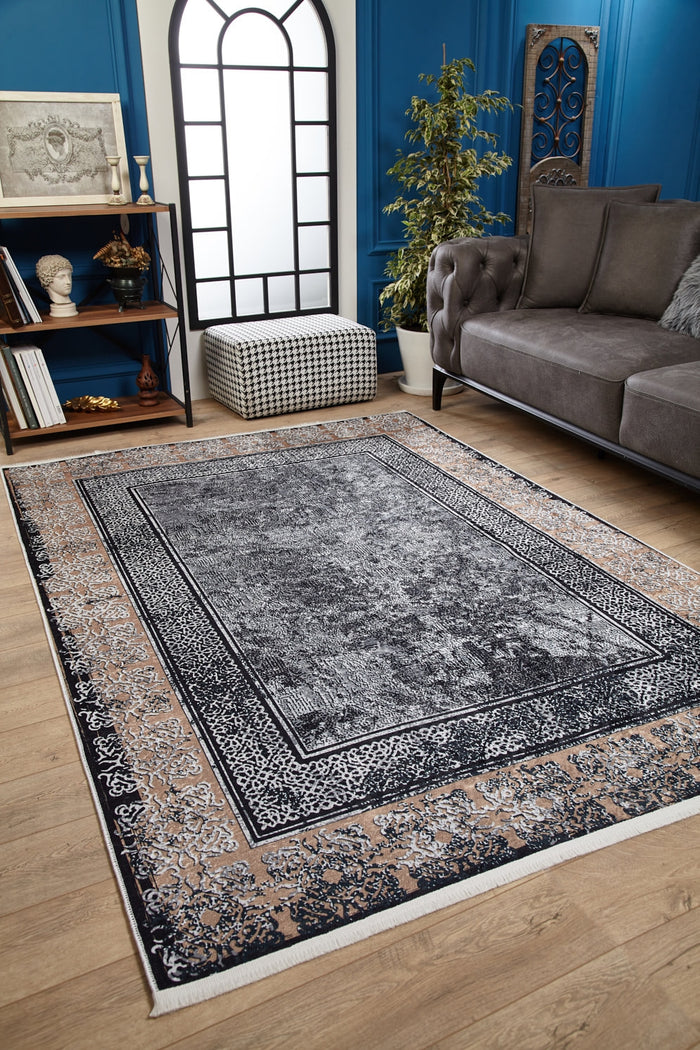 A stylish living room features the Contemporary Borderline - Washable Rug - JR1798 in gray on wood flooring, paired with a gray sofa, checkered pouf, tall potted plant, bookshelves, and blue walls lit by a large arched window.