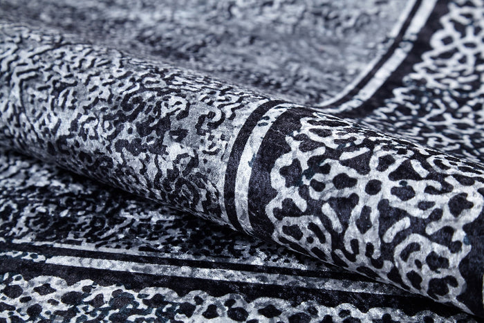 A close-up of the Contemporary Borderline - Washable Rug - JR1798 shows its intricate black and white abstract pattern with textured shapes and bold borders—an allergy-friendly, modern rug that brings elegance to any space.