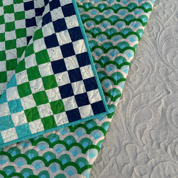 Close-up of various quilt patterns including checkered, scalloped, and textured.
