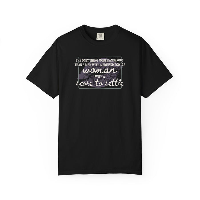A black Comfort Colors graphic tee from thtgrlreads featuring a bold typographic design saying "The only thing more dangerous than a man with a bruised ego is a woman with a score to settle," part of The Poison Daughter and Tees collections.