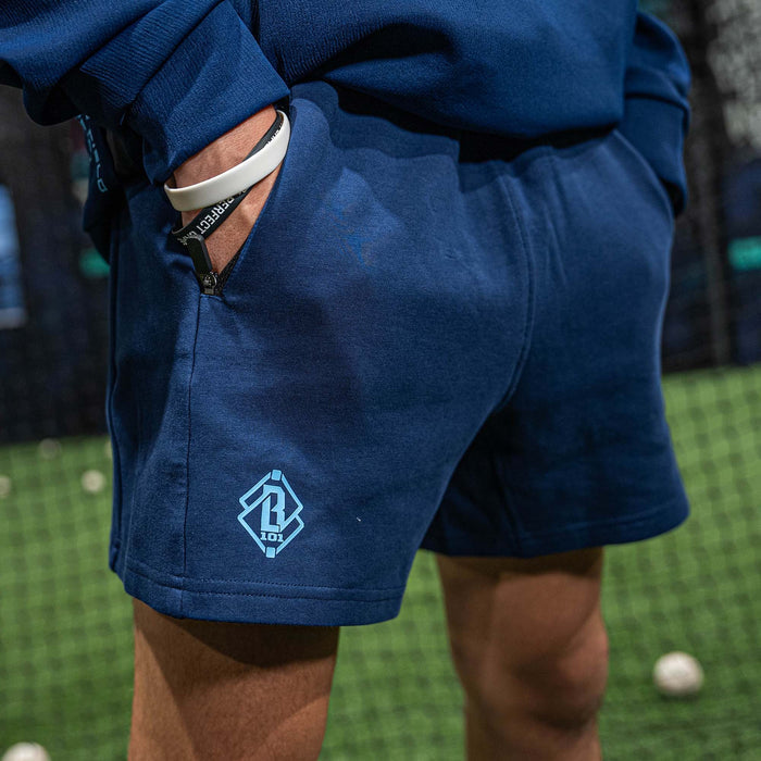 Person wearing blue shorts with a light blue BL101 logo on a sports field