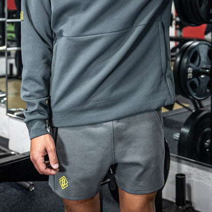 Person wearing a gray tracksuit with a yellow BL101 logo in a gym setting