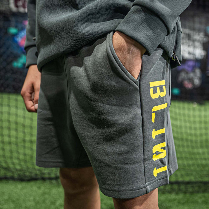 Person wearing gray shorts with 'BL101' text on a grassy field.