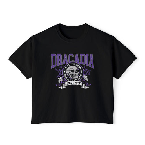 Nocticadia-themed crop top from thtgrlreads featuring vintage wash black Comfort Colors fabric with purple collegiate-style "Dracadia" text and skull graphic emblem, part of official licensed Tees collections.