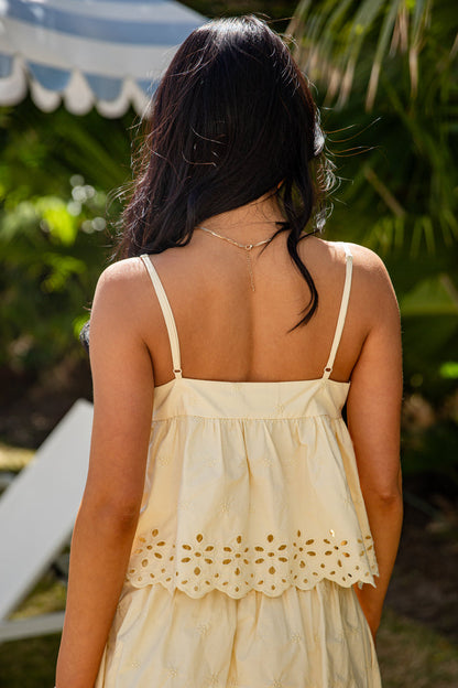 Woman wearing a light yellow dress with intricate detailing in an outdoor setting