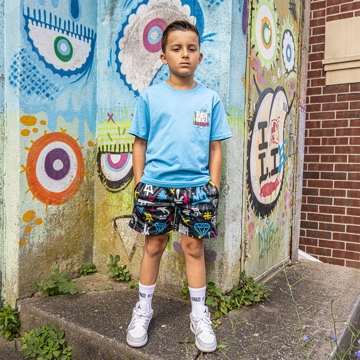 Youth model wearing multi-color youth shorts with “Graffiti Drip” design
