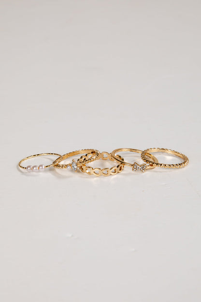 Set of gold rings with small stones on a light gray background