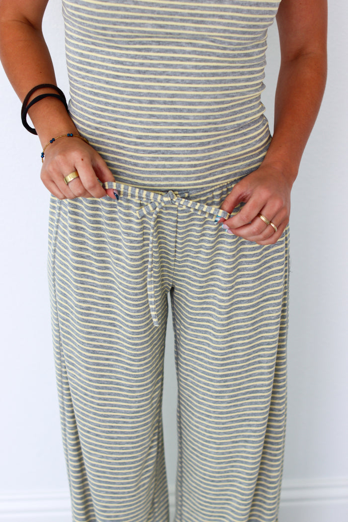 A person wearing a matching striped lounge set with a sleeveless top and wide-leg pants, shown from the chest down against a plain light background.