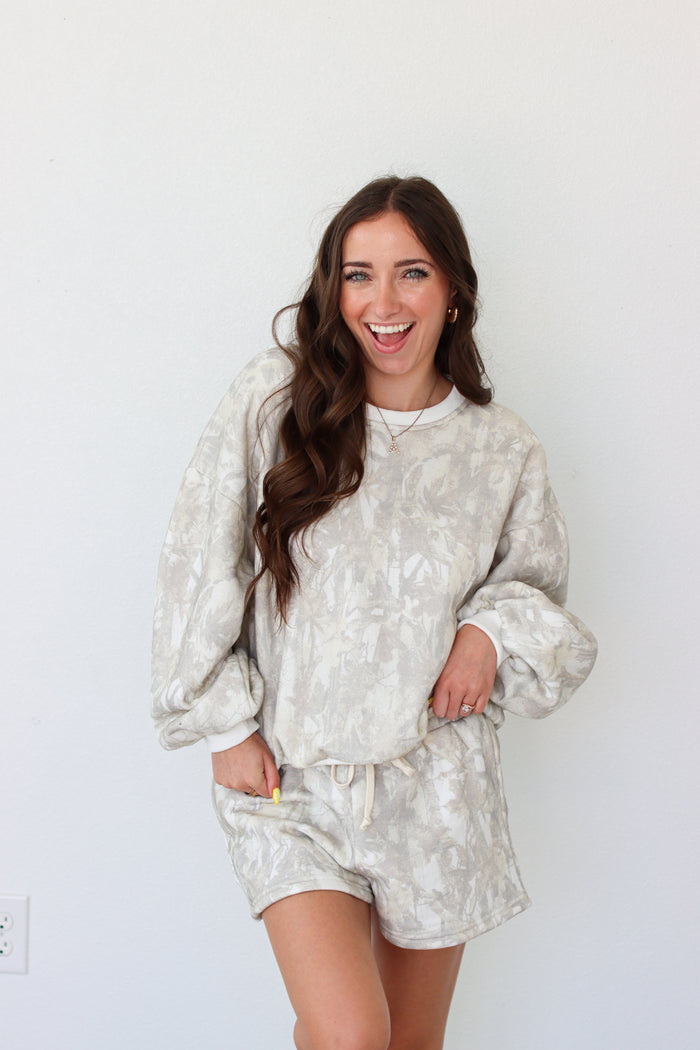 Woman wearing sweatshirt outfit with a camo pattern against a white background