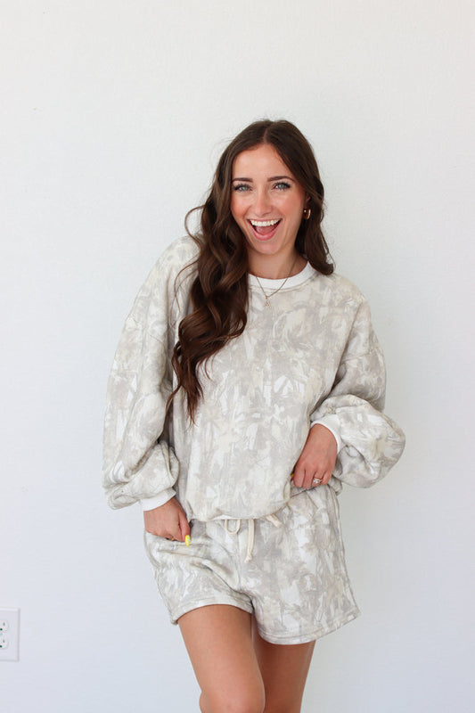 Woman wearing sweatshirt outfit with a camo pattern against a white background