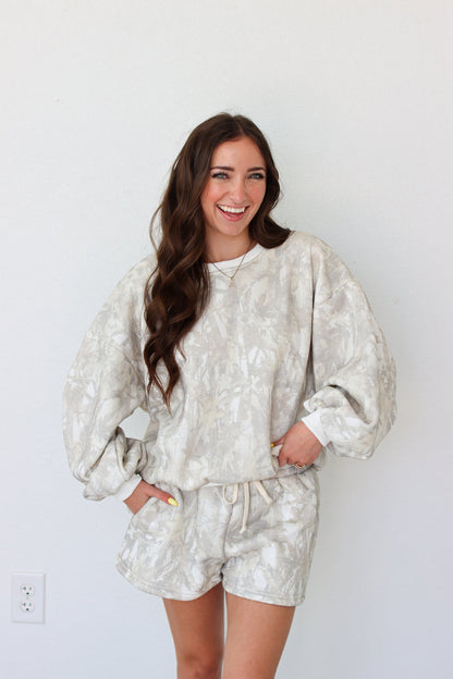 Woman wearing sweatshirt outfit with a camo pattern against a white background