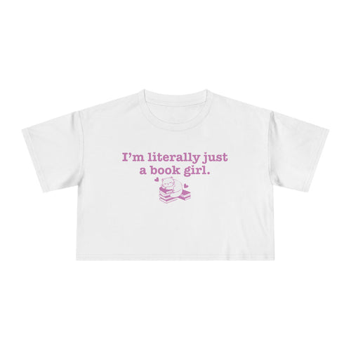 thtgrlreads officially licensed bookish apparel features this Printify white Comfort Colors crop top with vintage wash, soft fabric, and a purple graphic saying "I'm literally just a book girl" above a stack of books illustration, part of the Tees collection.