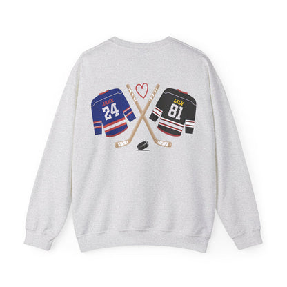 A thtgrlreads light gray Comfort Colors oversized crewneck sweatshirt from the Hockey Romance collection featuring a vintage graphic of crossed hockey sticks, a puck, and jerseys labeled "Jane 24" and "Lily 81" with a red heart above.