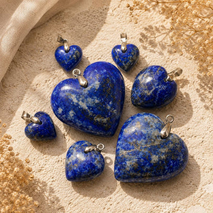 Lapis Lazuli heart pendants in assorted sizes displayed on a natural stone surface