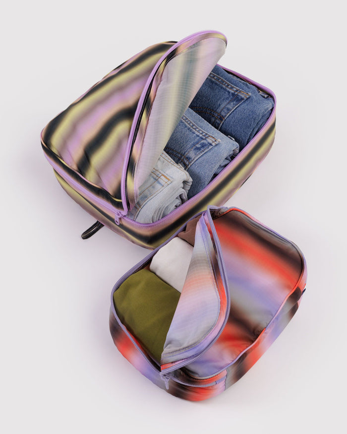 Gradient-striped packing cubes open with mesh lining and visible zippered pockets