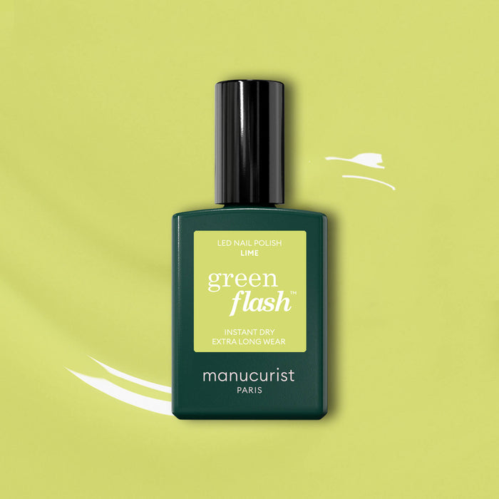 A bottle of Manucurist Lime Green Flash LED nail polish stands on a light green backdrop with white brushstroke accents, its dark green base topped with an anise green label.