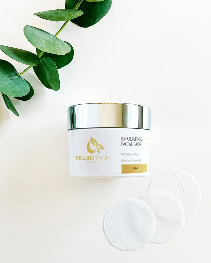 Angled photo of Reiland Exfoliating Facial Pads container highlighting luxury gold logo and clean label design with key benefits for skincare routine.