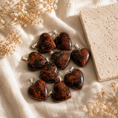 Mahogany Obsidian heart pendants displayed on a natural stone surface