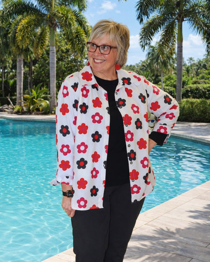 Woman wearing a floral jacket by a pool with palm trees in the background
