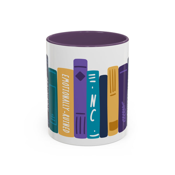 White ceramic mug with a purple interior featuring a colorful graphic of upright books with titles like "Emotionally-Ruined" in a bold, blocky illustration style.