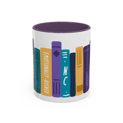 White ceramic mug with a purple interior featuring a colorful graphic of upright books with titles like "Emotionally-Ruined" in a bold, blocky illustration style.