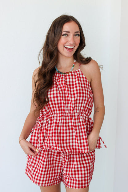 Woman wearing a red gingham shorts set against a white background