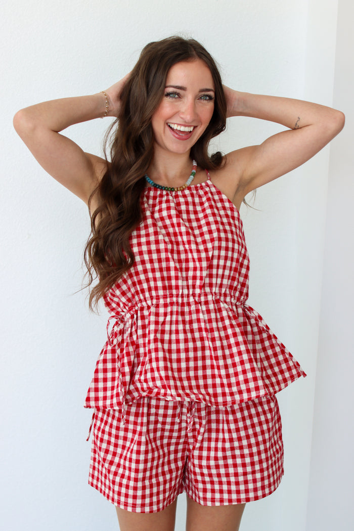 Woman wearing a red gingham shorts set against a white background