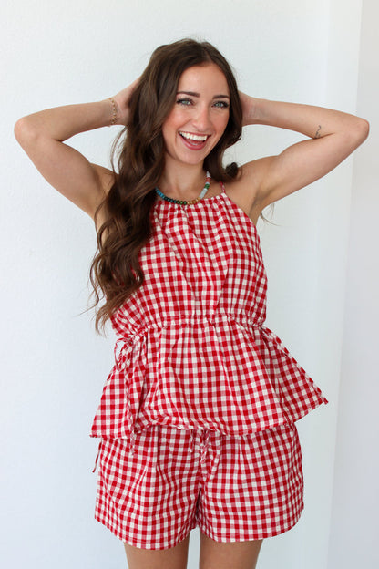 Woman wearing a red gingham shorts set against a white background