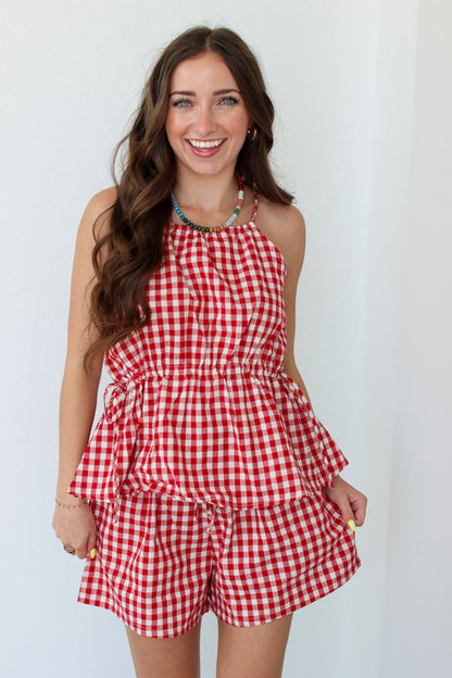 Woman wearing a red gingham shorts set against a white background